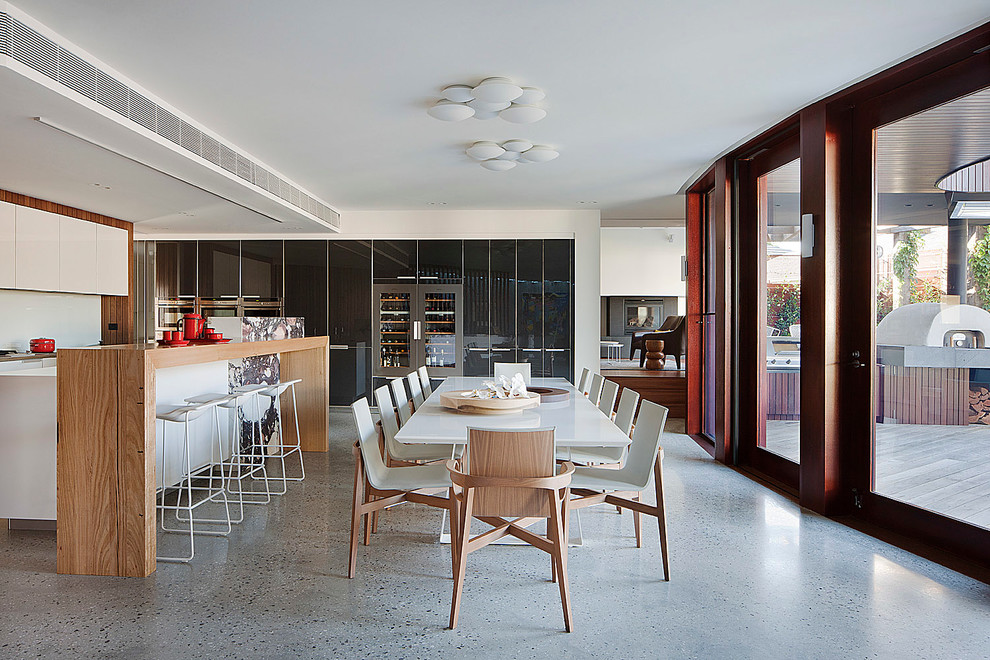 Immagine di una grande sala da pranzo aperta verso la cucina minimal con pavimento in cemento e pareti bianche