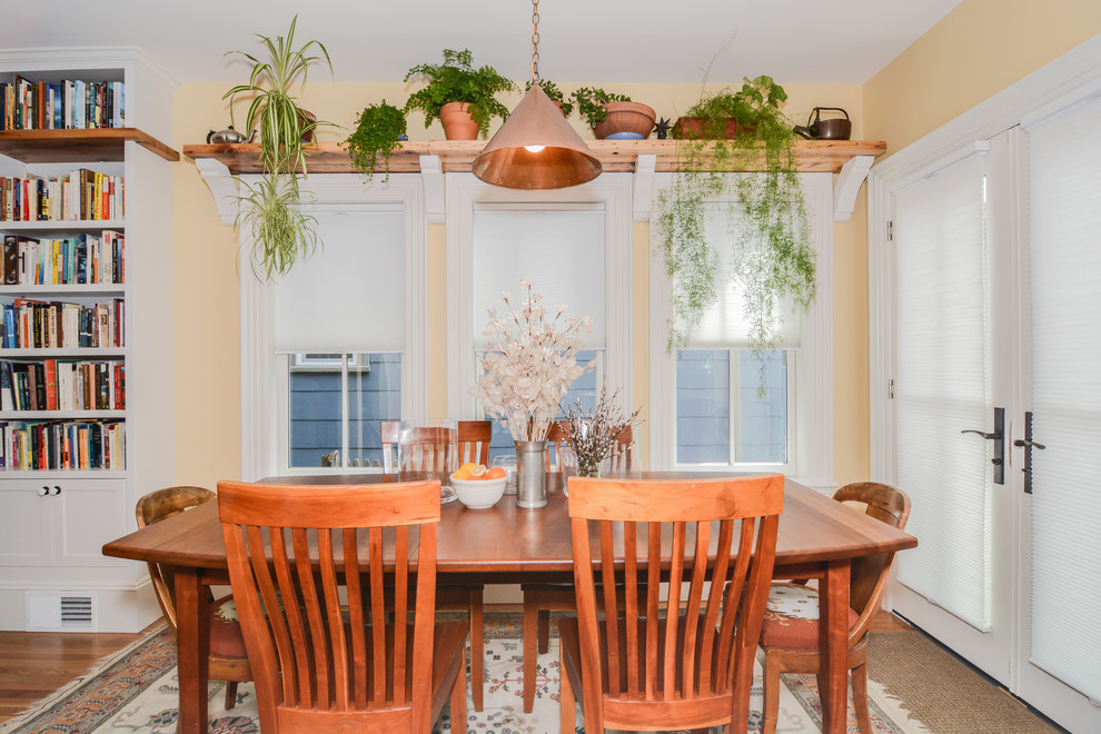 Immagine di una sala da pranzo aperta verso la cucina stile rurale di medie dimensioni con pareti gialle, pavimento in legno massello medio e nessun camino