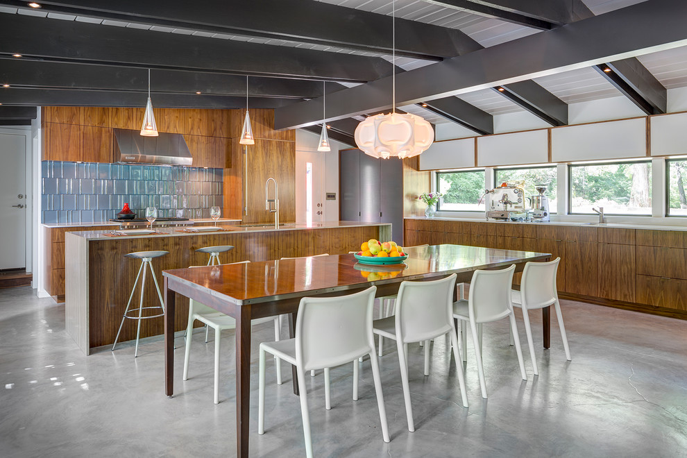 Foto di una sala da pranzo aperta verso la cucina minimalista con pavimento in cemento