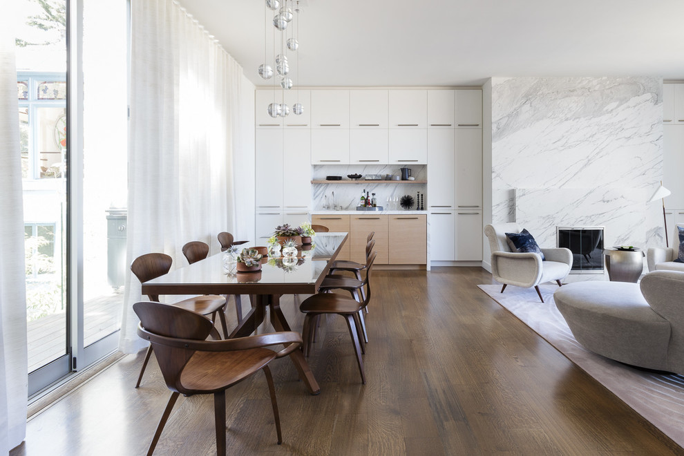 Réalisation d'une salle à manger ouverte sur le salon design avec un mur blanc, un sol en bois brun, un sol marron et une cheminée standard.