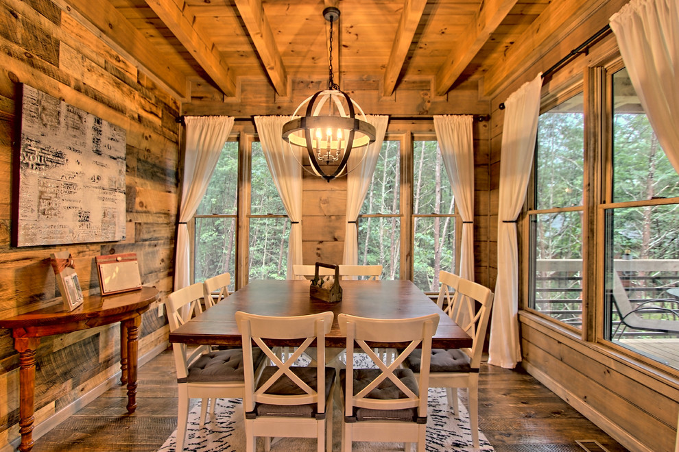 На фото: маленькая гостиная-столовая в стиле рустика с серыми стенами, деревянным полом, стандартным камином, фасадом камина из камня и коричневым полом для на участке и в саду