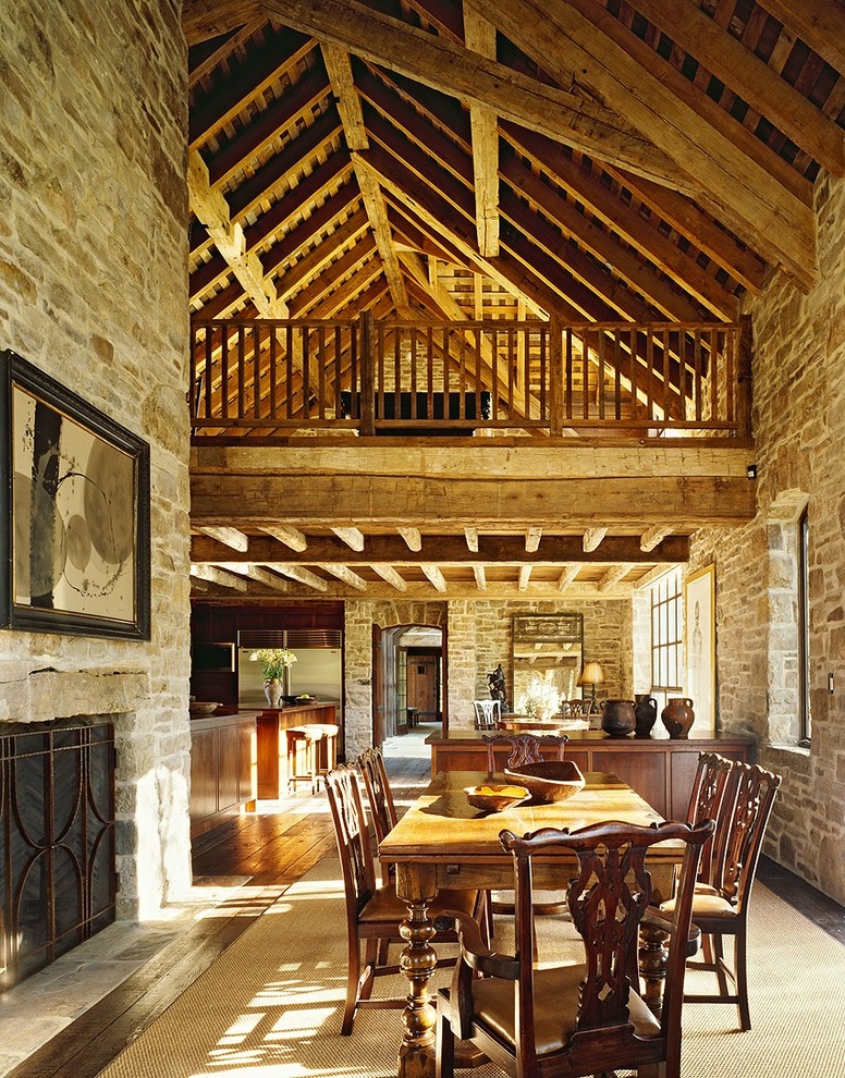 Inspiration pour une salle à manger ouverte sur le salon chalet avec parquet foncé, une cheminée standard et un manteau de cheminée en pierre.