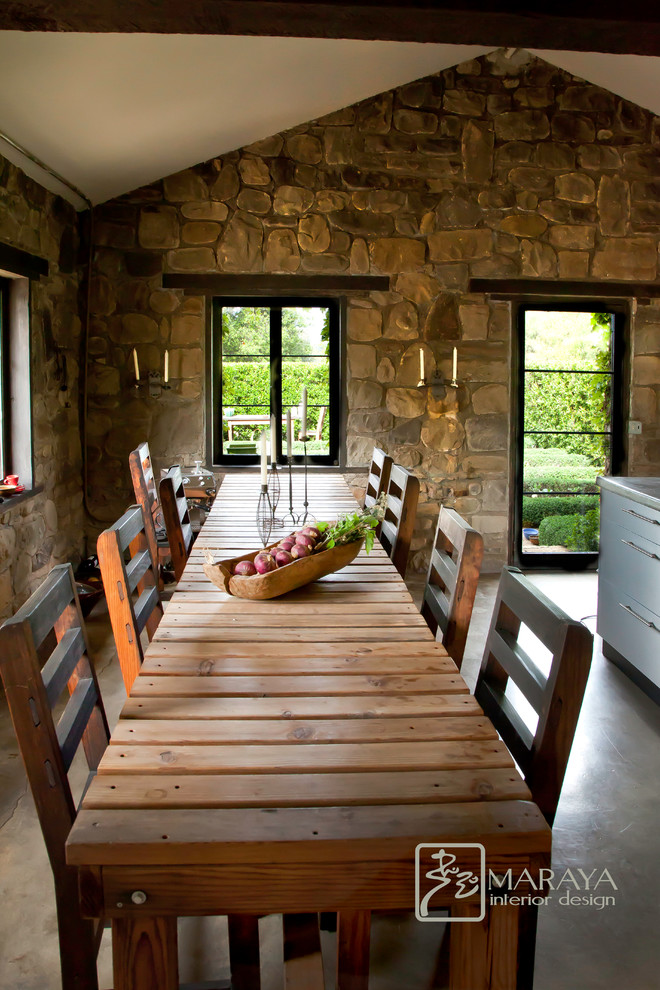 Пример оригинального дизайна: гостиная-столовая среднего размера в стиле рустика с бетонным полом, бежевыми стенами, стандартным камином и фасадом камина из камня