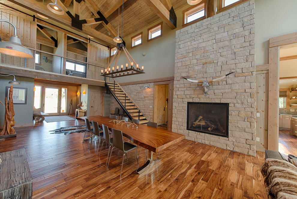 Large rustic open plan dining room in Boise with medium hardwood flooring, a standard fireplace and a stone fireplace surround.