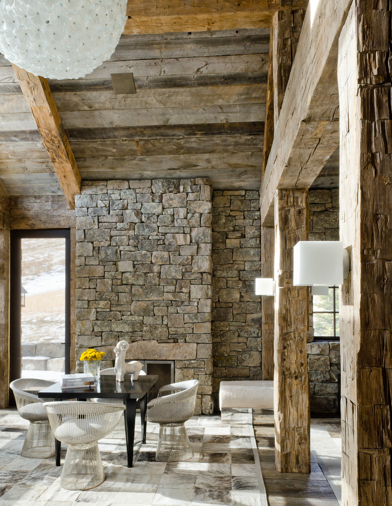 Cette image montre une salle à manger chalet avec une cheminée standard et un manteau de cheminée en pierre.