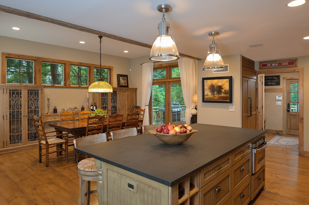 Immagine di una grande sala da pranzo aperta verso la cucina stile rurale con pareti beige e pavimento in legno massello medio