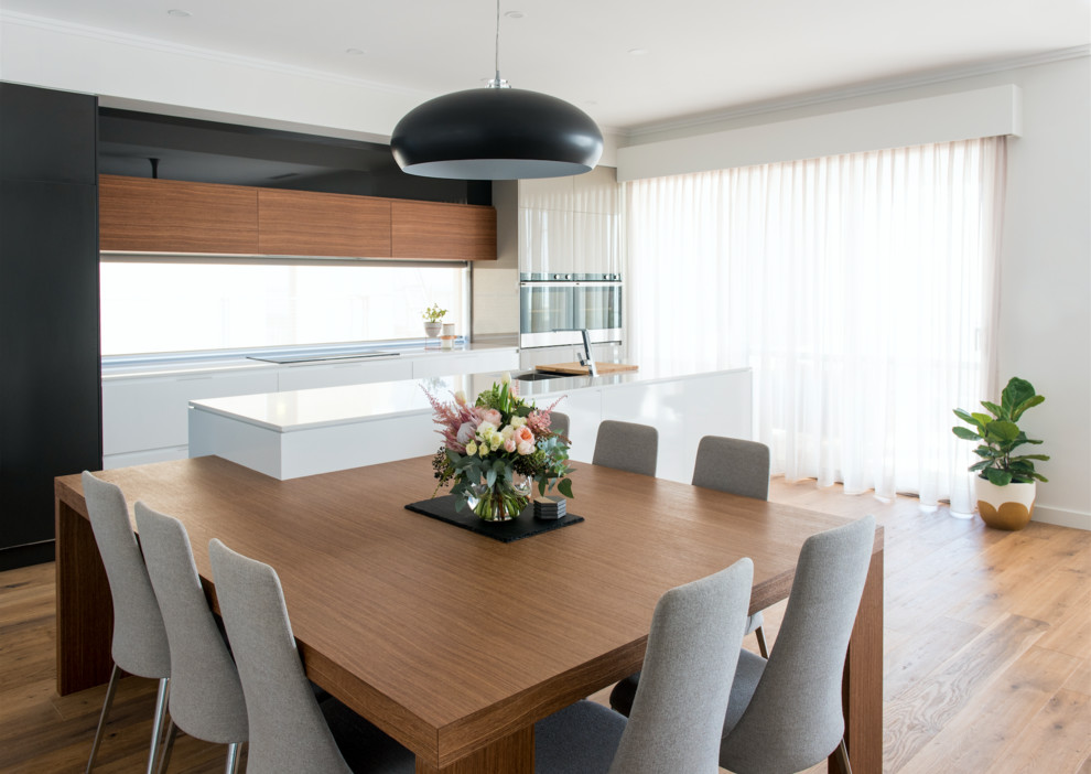 Foto di una sala da pranzo aperta verso la cucina contemporanea con pareti bianche, parquet chiaro, nessun camino e pavimento beige