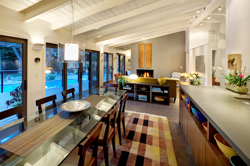 Cette image montre une salle à manger ouverte sur le salon vintage de taille moyenne avec un mur blanc, aucune cheminée et un sol marron.