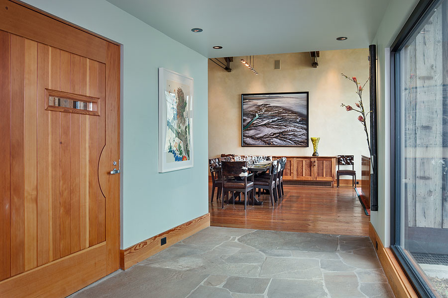 Immagine di una sala da pranzo minimal con pareti beige, parquet chiaro, camino classico e cornice del camino in pietra