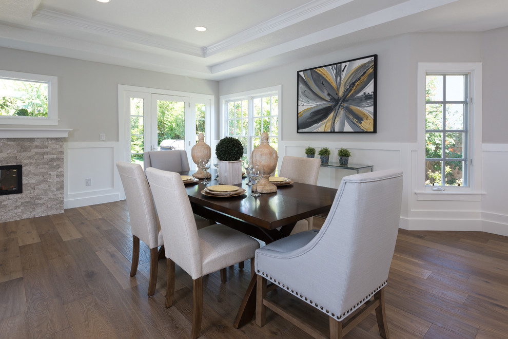 Example of a large trendy medium tone wood floor kitchen/dining room combo design in San Diego with gray walls, a ribbon fireplace and a stone fireplace