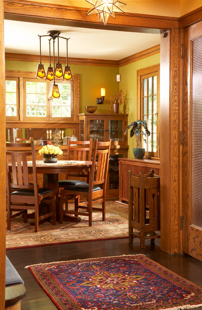 Cette image montre une salle à manger craftsman fermée avec un mur jaune, parquet foncé et aucune cheminée.