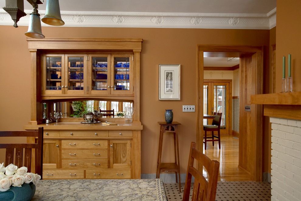 На фото: отдельная столовая в классическом стиле с коричневыми стенами, стандартным камином и фасадом камина из кирпича с