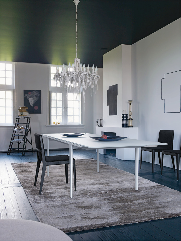 Cette image montre une salle à manger design avec un mur blanc, parquet peint, une cheminée ribbon et un manteau de cheminée en plâtre.