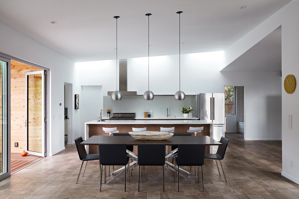 Cette photo montre une salle à manger ouverte sur la cuisine rétro de taille moyenne avec un mur blanc, un sol en carrelage de porcelaine et un sol marron.