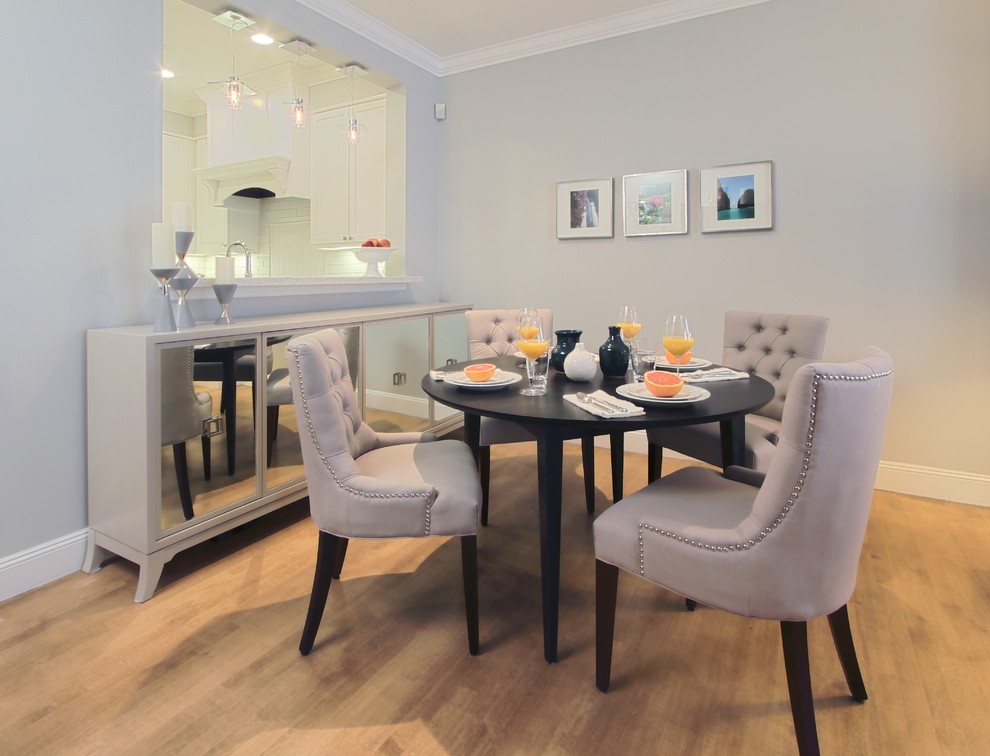 Immagine di una sala da pranzo aperta verso la cucina design con pareti grigie e parquet chiaro