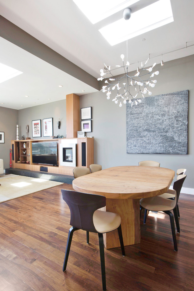 Exemple d'une grande salle à manger ouverte sur la cuisine tendance avec un mur multicolore, un sol en bois brun, une cheminée standard et un manteau de cheminée en métal.