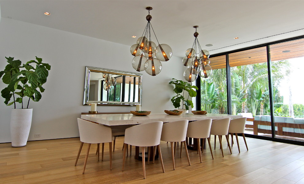 Diseño de comedor minimalista grande abierto con paredes blancas, suelo de madera clara y suelo beige