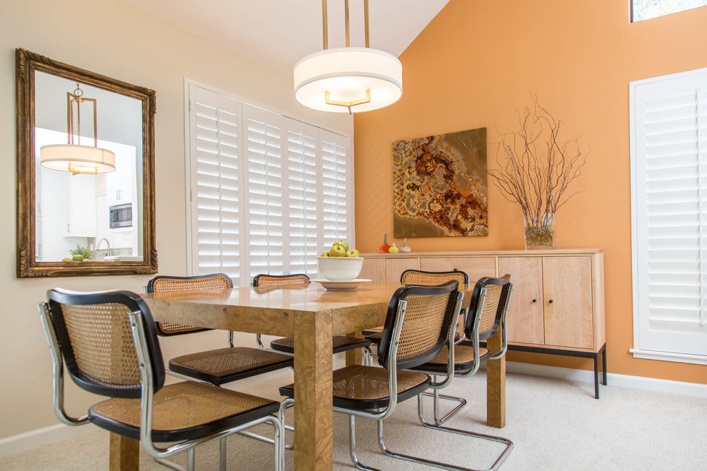 Example of a mid-sized trendy carpeted kitchen/dining room combo design in San Francisco with orange walls, a standard fireplace and a stone fireplace
