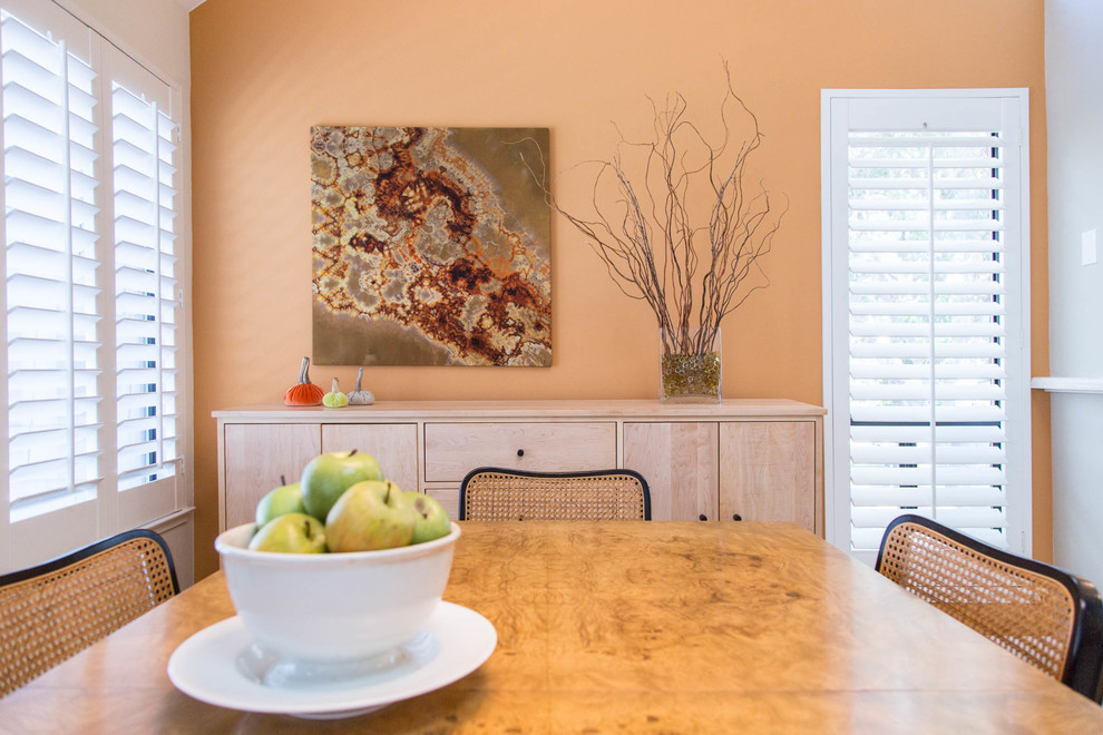 На фото: кухня-столовая среднего размера в современном стиле с оранжевыми стенами, ковровым покрытием, стандартным камином и фасадом камина из камня с