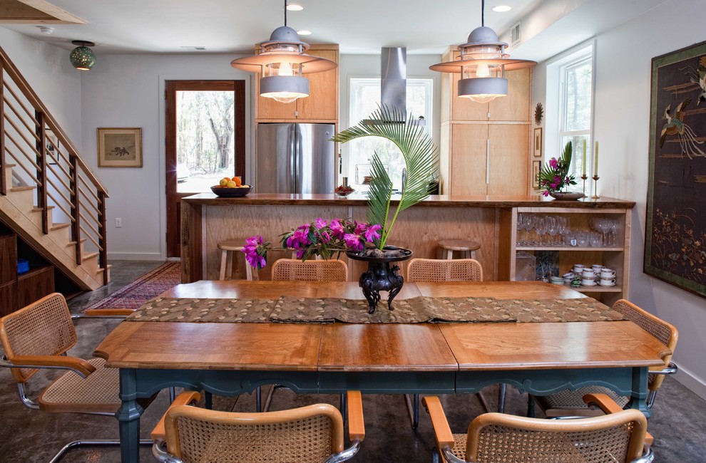 Exemple d'une petite salle à manger ouverte sur la cuisine tendance avec un mur blanc et sol en béton ciré.