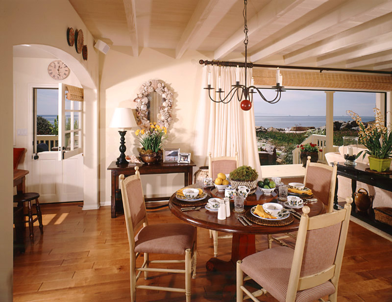 Aménagement d'une salle à manger ouverte sur le salon bord de mer avec un mur beige et un sol en bois brun.