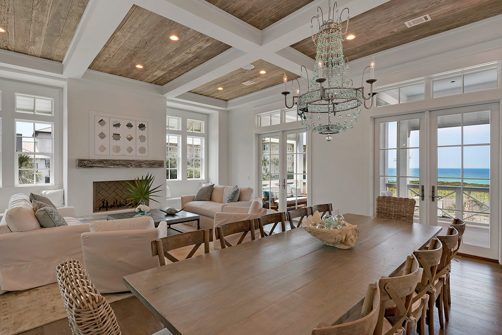 Immagine di una sala da pranzo aperta verso la cucina stile marinaro di medie dimensioni con pareti bianche, pavimento in legno massello medio, camino classico, cornice del camino in intonaco e pavimento beige