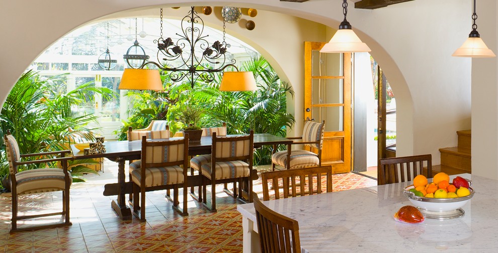This is an example of a mediterranean dining room in Orange County with white walls, ceramic flooring and feature lighting.