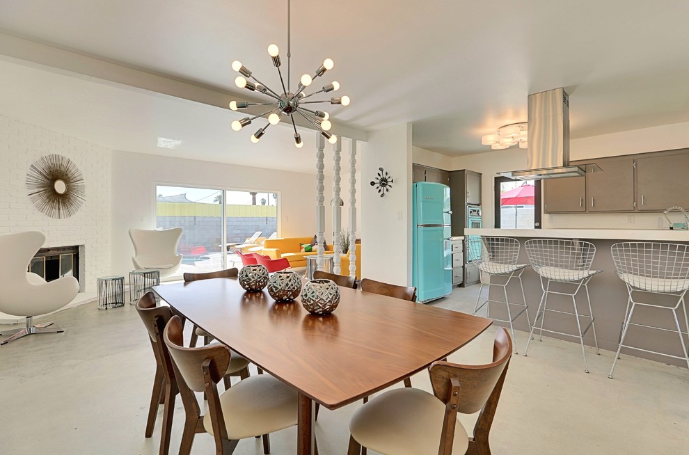 Inspiration pour une grande salle à manger ouverte sur la cuisine vintage avec un mur blanc, sol en béton ciré, une cheminée d'angle et un manteau de cheminée en brique.