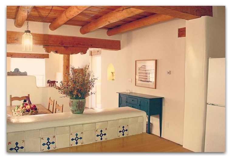Cette image montre une salle à manger ouverte sur la cuisine sud-ouest américain avec un mur blanc, un sol en carrelage de céramique, aucune cheminée et un sol marron.