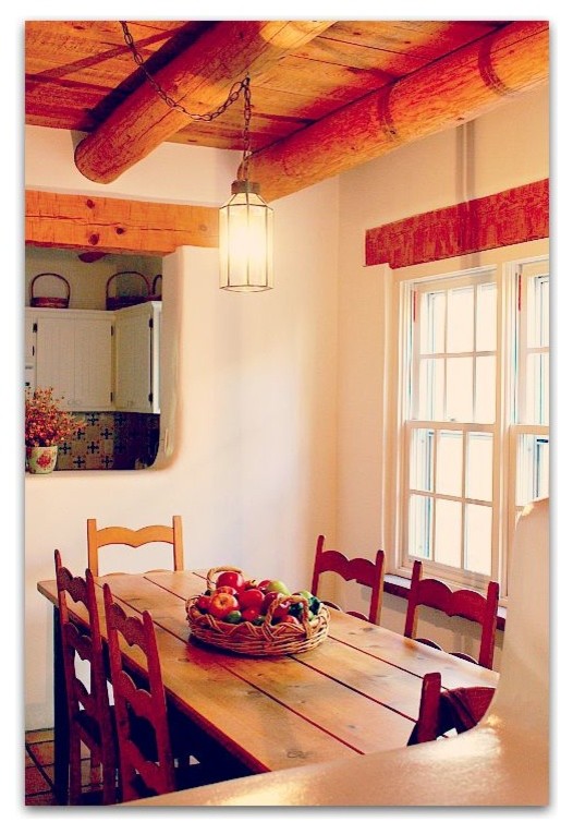 Cette photo montre une salle à manger ouverte sur la cuisine sud-ouest américain avec un mur blanc, un sol en carrelage de céramique, aucune cheminée et un sol marron.
