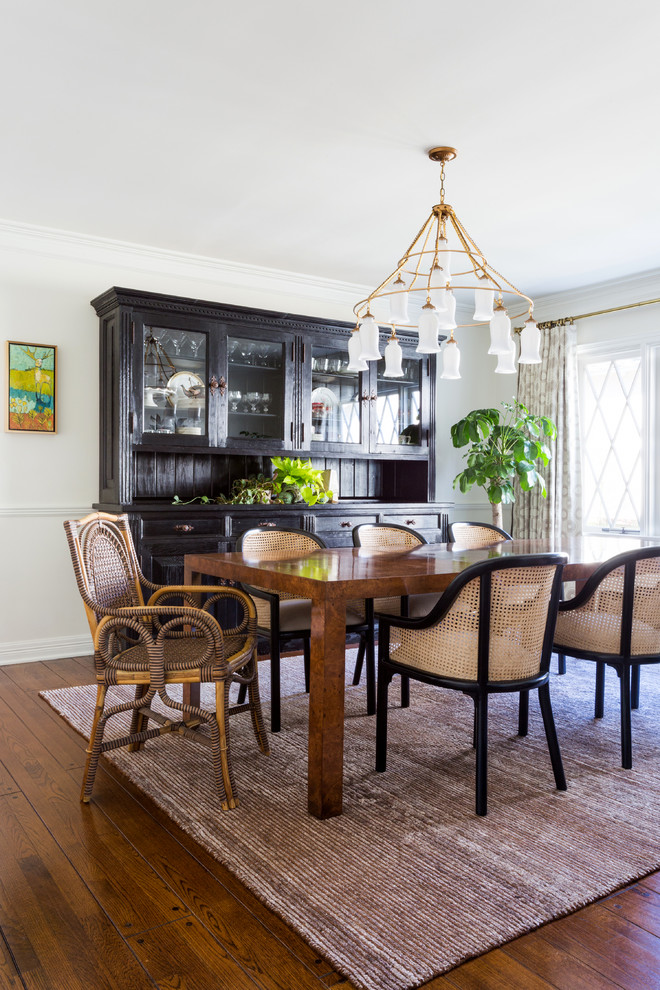 This is an example of a medium sized eclectic enclosed dining room in Los Angeles with white walls, medium hardwood flooring, brown floors, no fireplace and a dado rail.