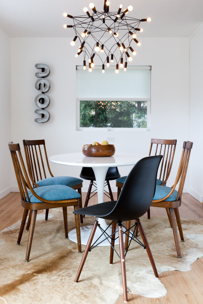 Example of an eclectic medium tone wood floor dining room design in Los Angeles with white walls