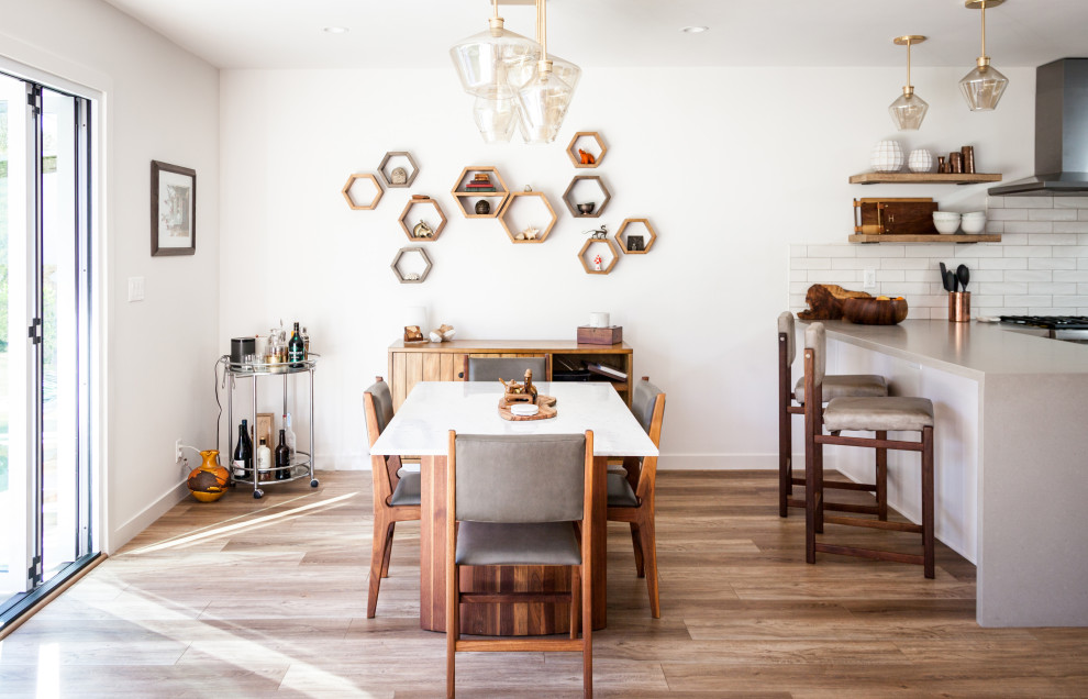 Esempio di una sala da pranzo aperta verso il soggiorno moderna di medie dimensioni con pareti bianche, pavimento in laminato e pavimento marrone