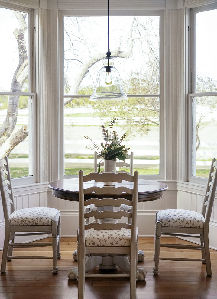 Immagine di una piccola sala da pranzo aperta verso il soggiorno country con pareti bianche, pavimento in legno massello medio e pavimento marrone