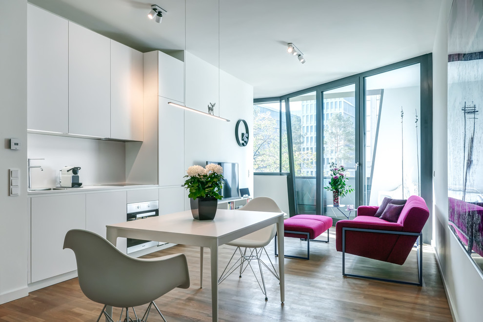 Mittelgroße Moderne Wohnküche ohne Kamin mit weißer Wandfarbe, braunem Holzboden und braunem Boden in Berlin
