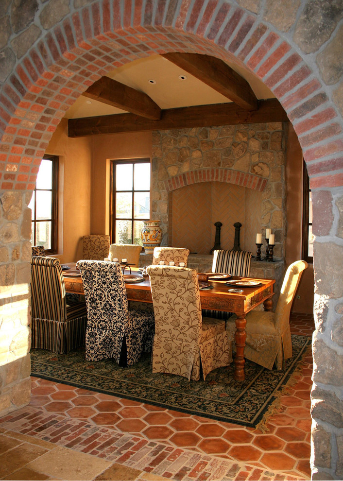 Inspiration för rustika matplatser, med orange väggar, en standard öppen spis, en spiselkrans i sten och klinkergolv i terrakotta