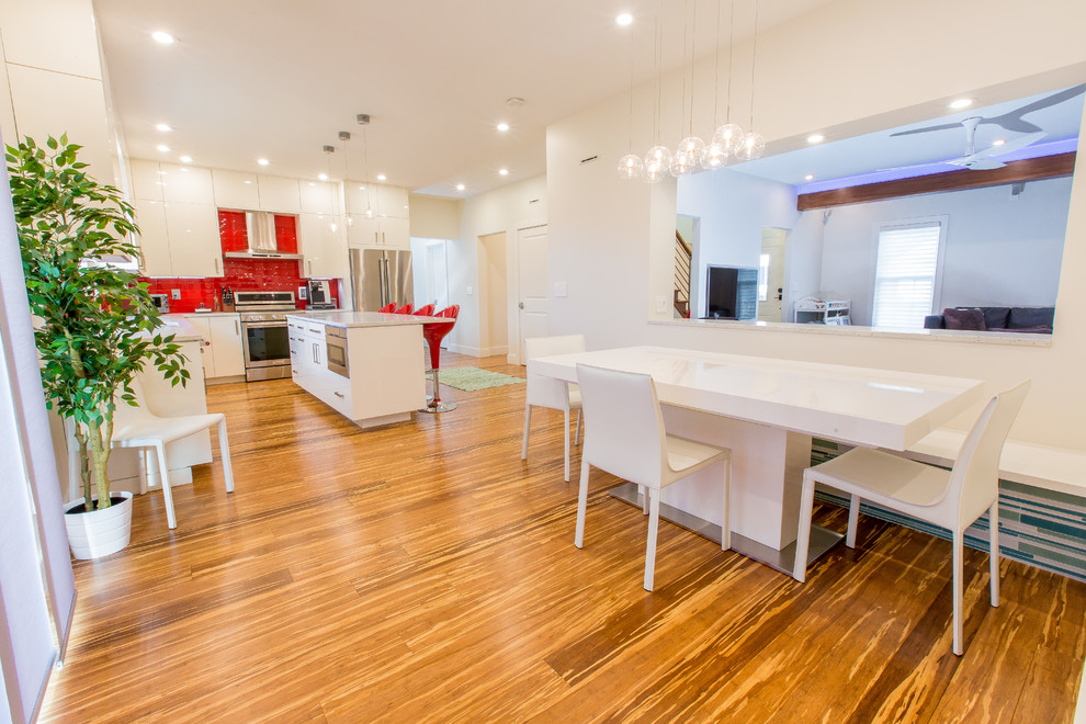 Idée de décoration pour une salle à manger ouverte sur la cuisine design de taille moyenne avec un mur blanc, parquet en bambou et un sol marron.