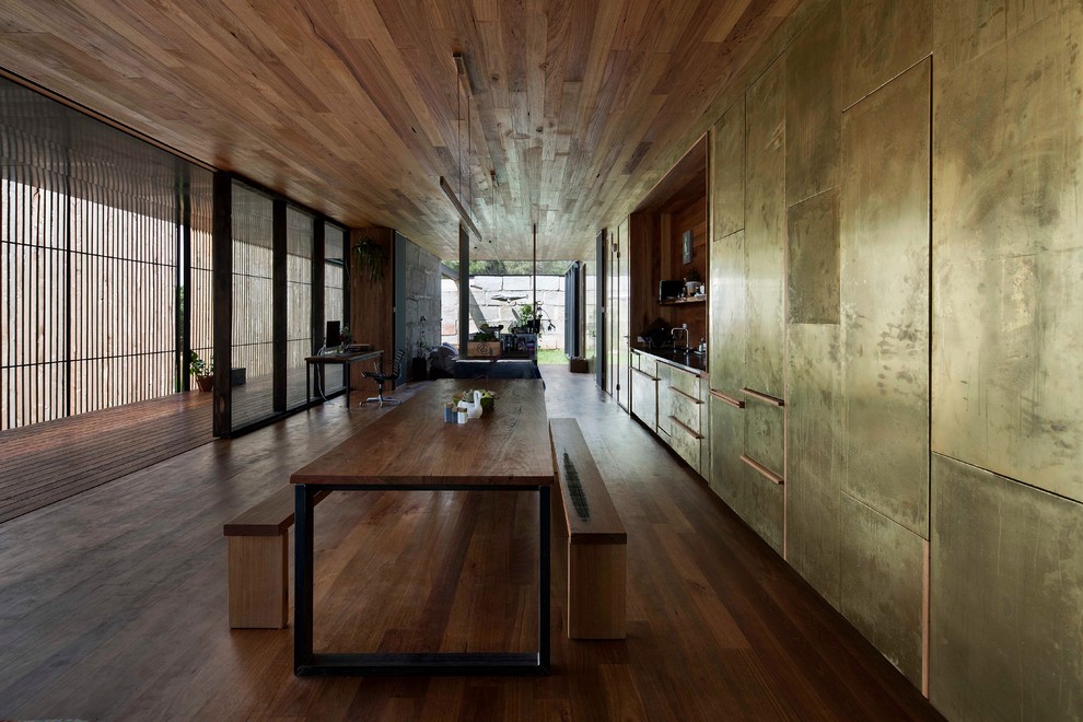 Réalisation d'une salle à manger ouverte sur la cuisine minimaliste avec mur métallisé et parquet foncé.