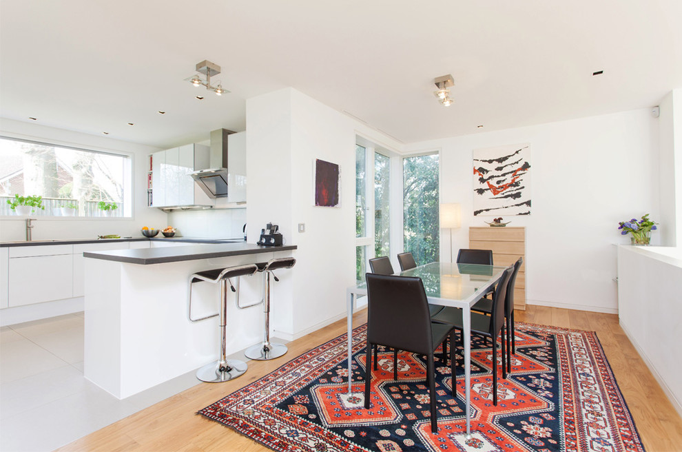 Inspiration pour une salle à manger ouverte sur la cuisine design avec un mur blanc, un sol en bois brun et éclairage.