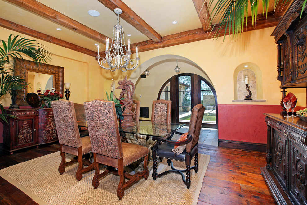 Example of a mid-sized tuscan medium tone wood floor enclosed dining room design in Orange County with yellow walls and no fireplace