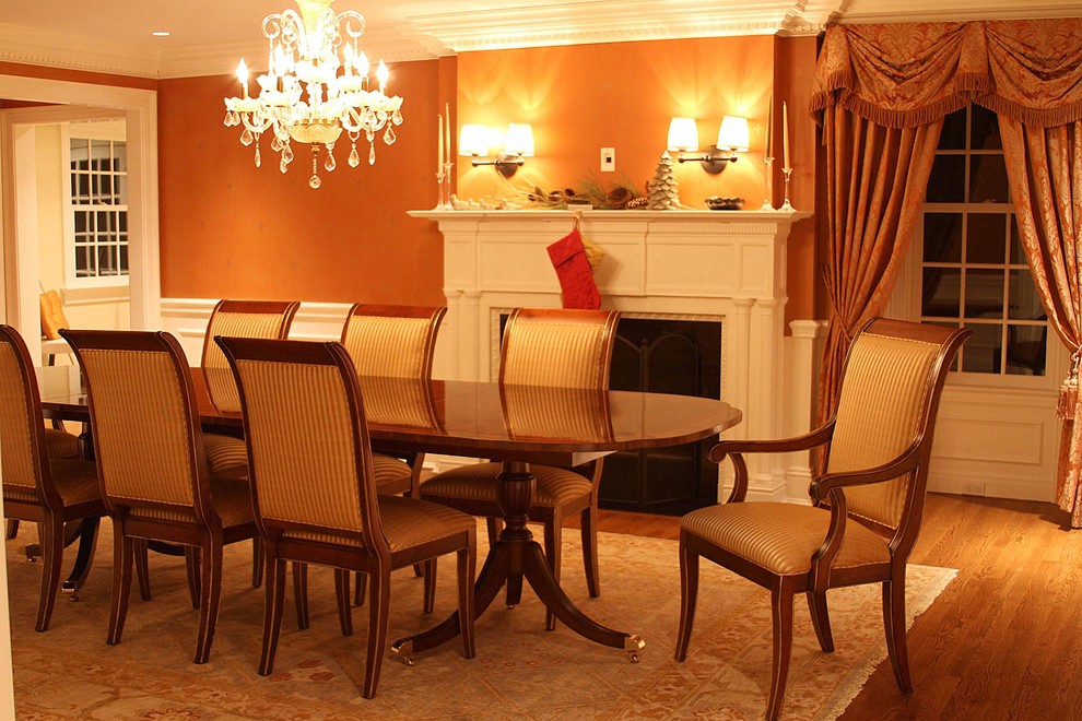 Idee per una sala da pranzo classica chiusa e di medie dimensioni con pareti arancioni, pavimento in legno massello medio e camino classico