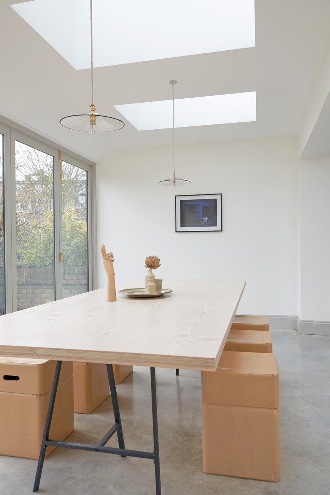 Photo of a scandinavian dining room in London with concrete flooring, white walls and grey floors.