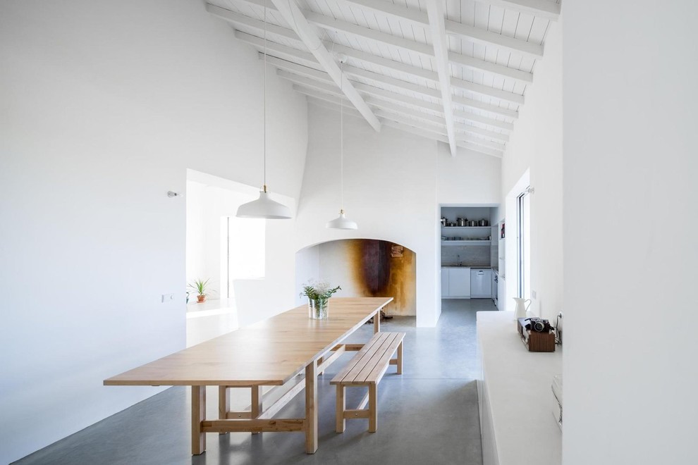 Inspiration för mellanstora minimalistiska separata matplatser, med vita väggar, betonggolv, en spiselkrans i gips och en standard öppen spis