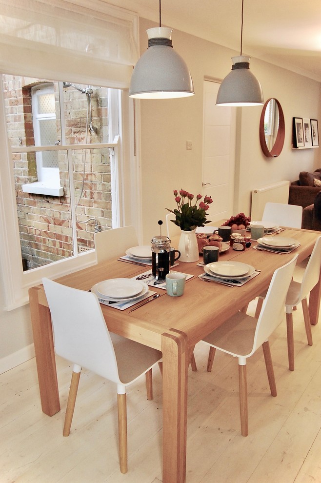Exemple d'une salle à manger ouverte sur le salon scandinave de taille moyenne avec un mur gris, parquet clair, un poêle à bois, un manteau de cheminée en brique et un sol blanc.
