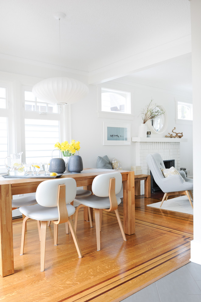 Foto di una piccola sala da pranzo aperta verso la cucina minimalista con pareti bianche, pavimento in legno massello medio e nessun camino