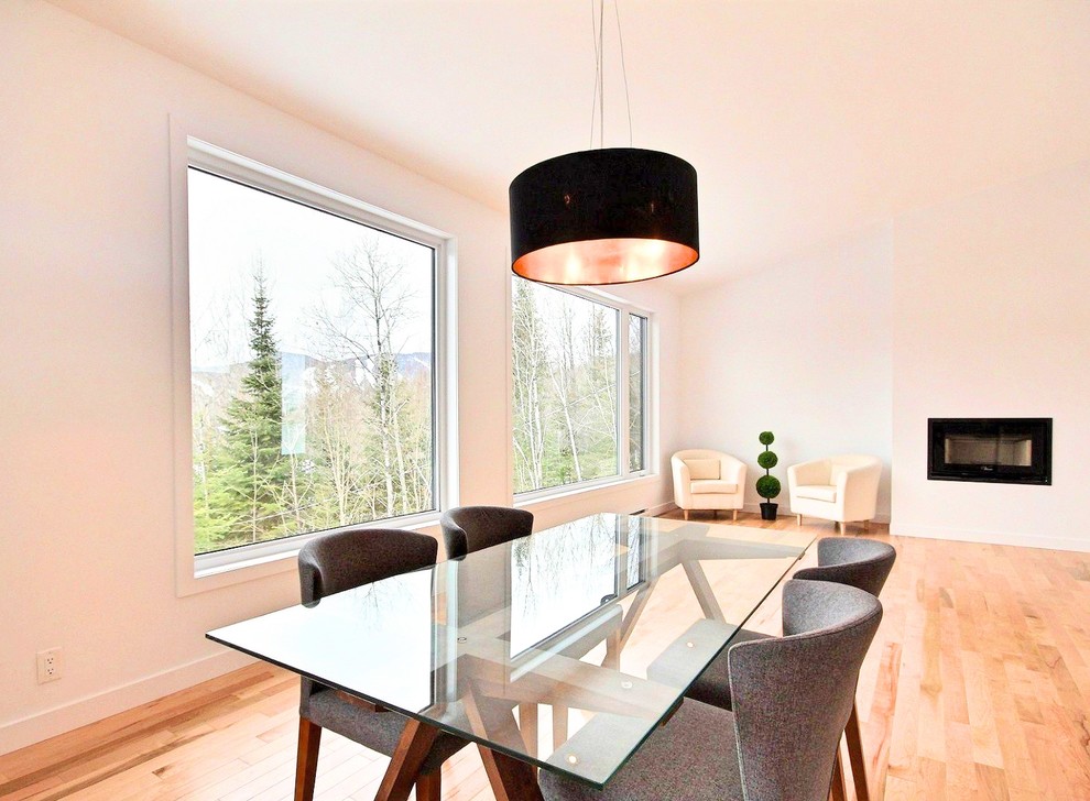 На фото: гостиная-столовая среднего размера в скандинавском стиле с белыми стенами, светлым паркетным полом, подвесным камином, фасадом камина из штукатурки и бежевым полом с