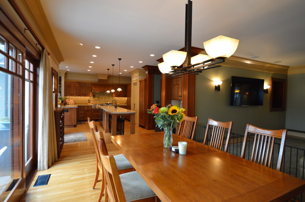 Immagine di una sala da pranzo aperta verso la cucina american style con pareti verdi, parquet chiaro e nessun camino
