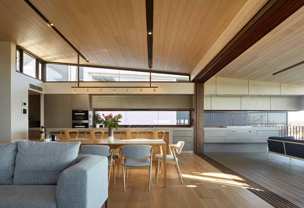 Offenes Modernes Esszimmer mit beiger Wandfarbe, hellem Holzboden und beigem Boden in Sunshine Coast
