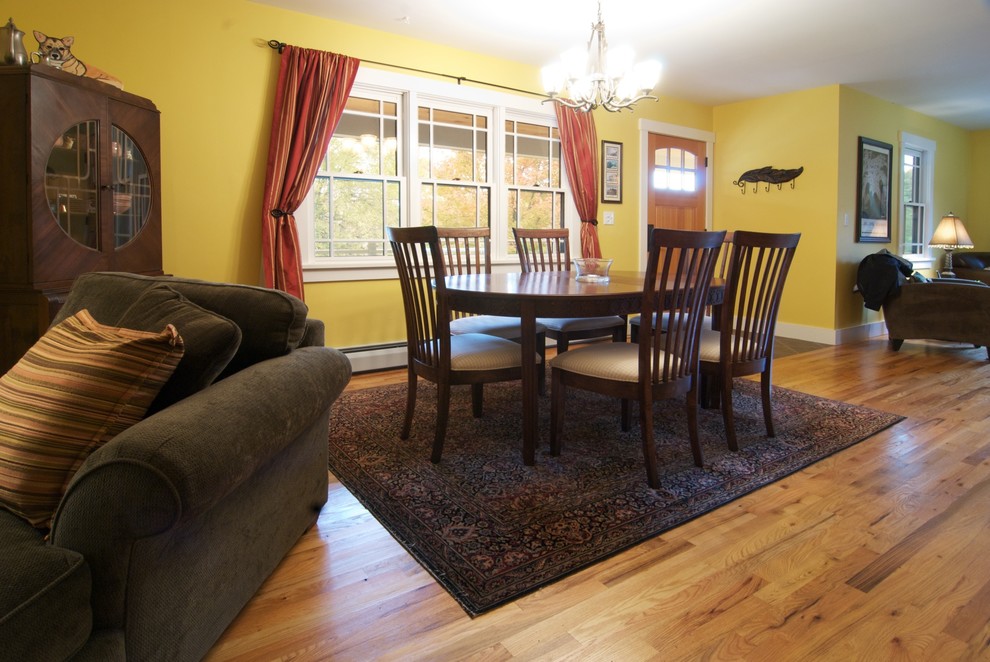Foto di una sala da pranzo aperta verso il soggiorno stile americano di medie dimensioni con pareti gialle, pavimento in legno massello medio e nessun camino