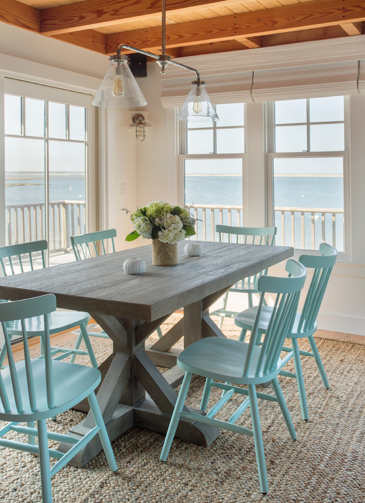 Immagine di una sala da pranzo aperta verso il soggiorno stile marino con pareti gialle e pavimento in legno massello medio